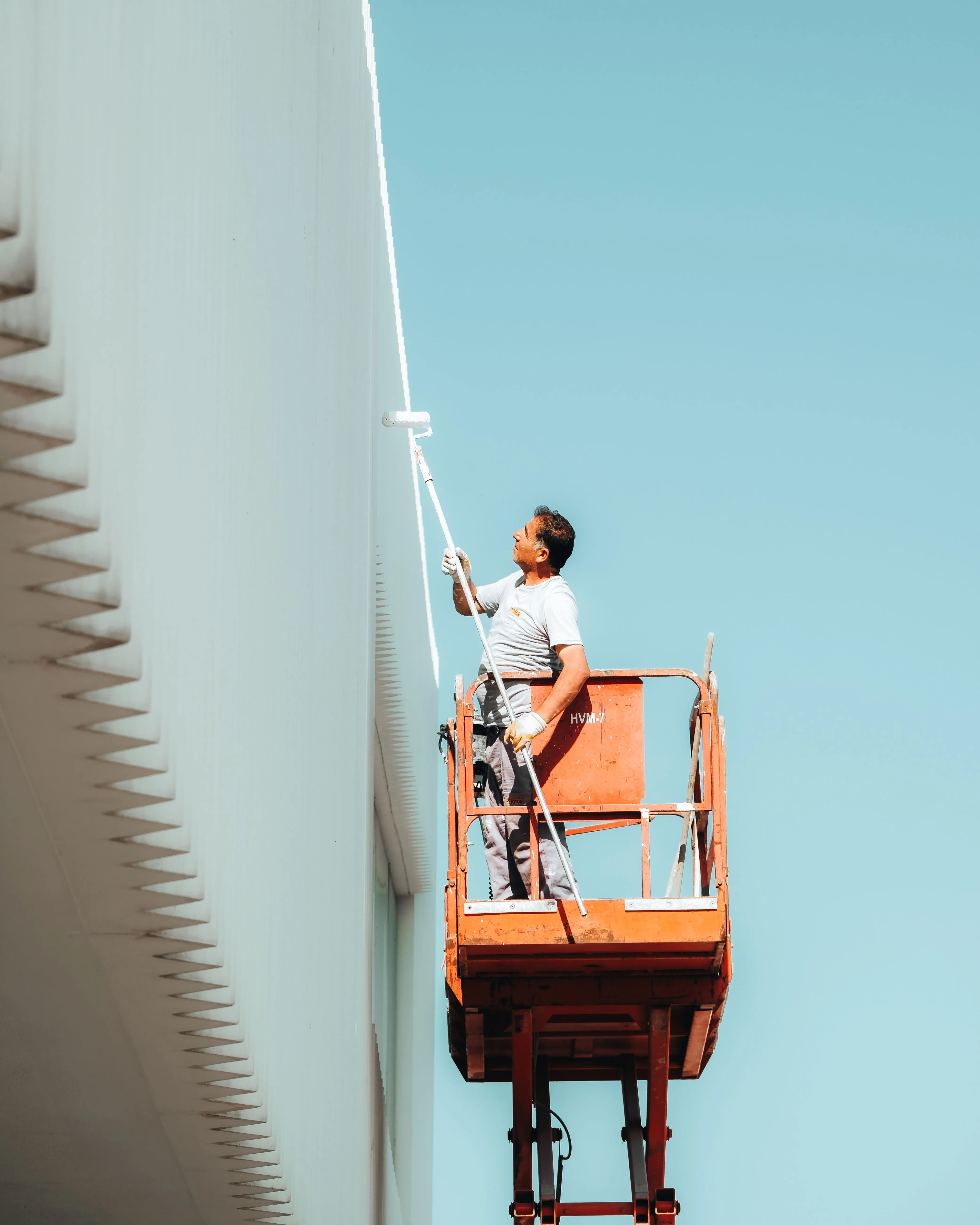 Peintre sur une nacelle appliquant de la peinture sur une façade